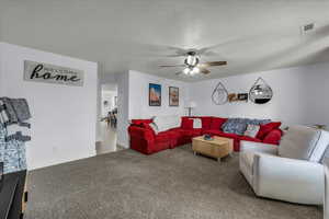 Living area with carpet floors, ceiling fan, and a textured ceiling