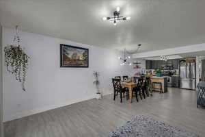 Dining space featuring a textured ceiling, light wood-type flooring, and a chandelier