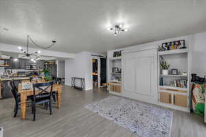 Dining room featuring a barn door, light wood-style flooring, a textured ceiling, and suspended lighting
