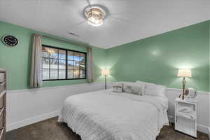 Bedroom with dark colored carpet and a textured ceiling