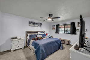 Bedroom featuring light colored carpet, ceiling fan, and a textured ceiling