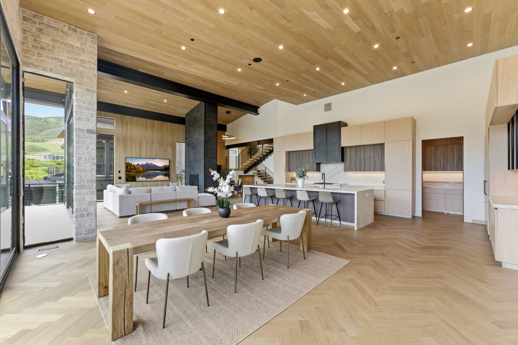 Open-concept living space featuring wood-finish flooring in a herringbone pattern and a wood-paneled ceiling with recessed lighting
