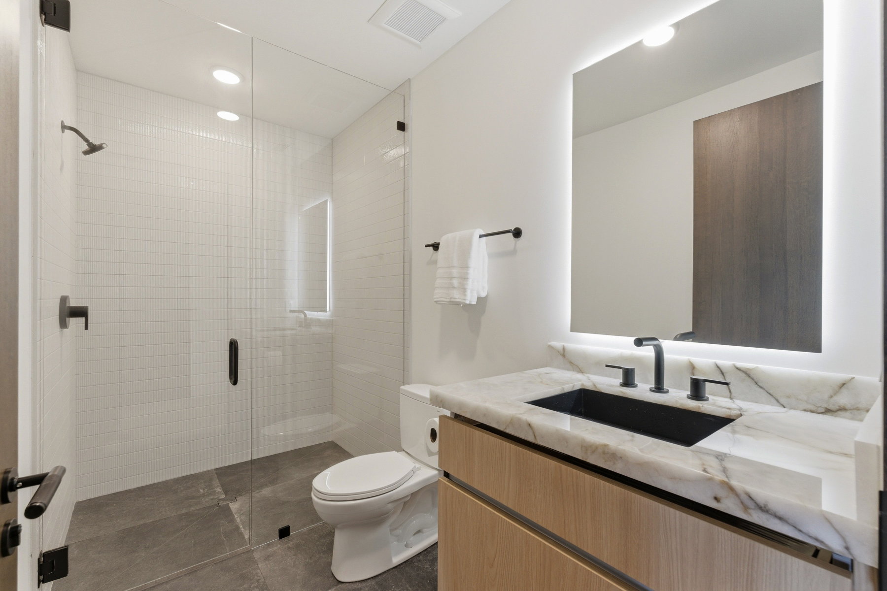Contemporary bathroom featuring a floating vanity with a marble-finish countertop, undermount black sink, and matte black fixtures