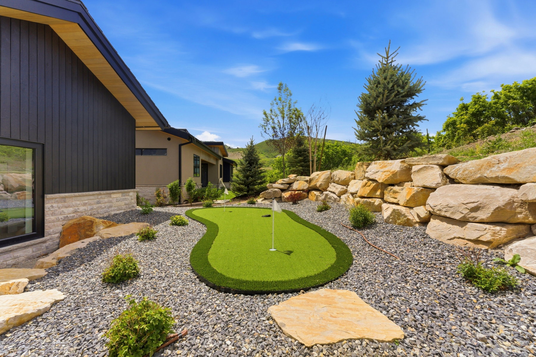 Outdoor putting green surrounded by gravel and natural stone landscaping