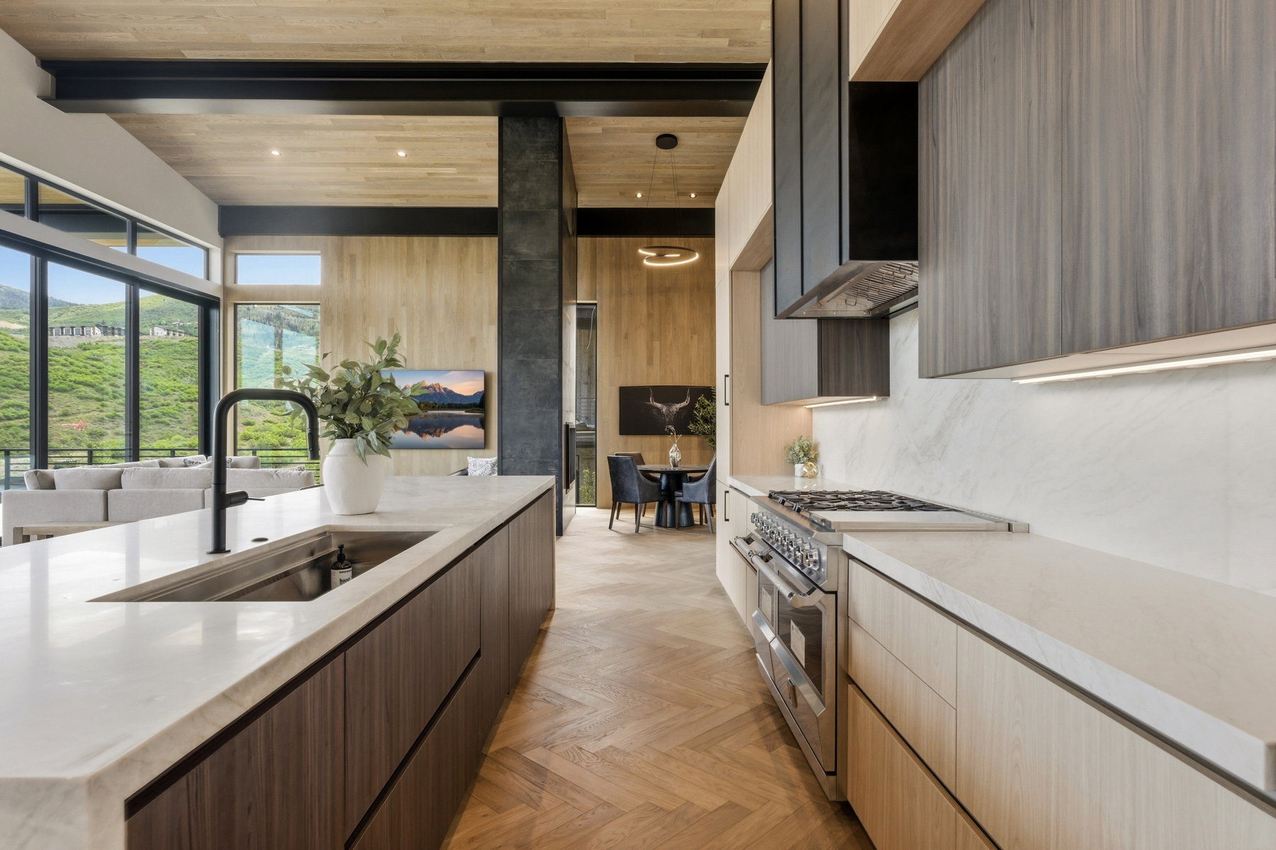 Gourmet kitchen featuring a large central island with an undermount sink, a professional-grade range, a stone slab backsplash, and wood-finish cabinetry