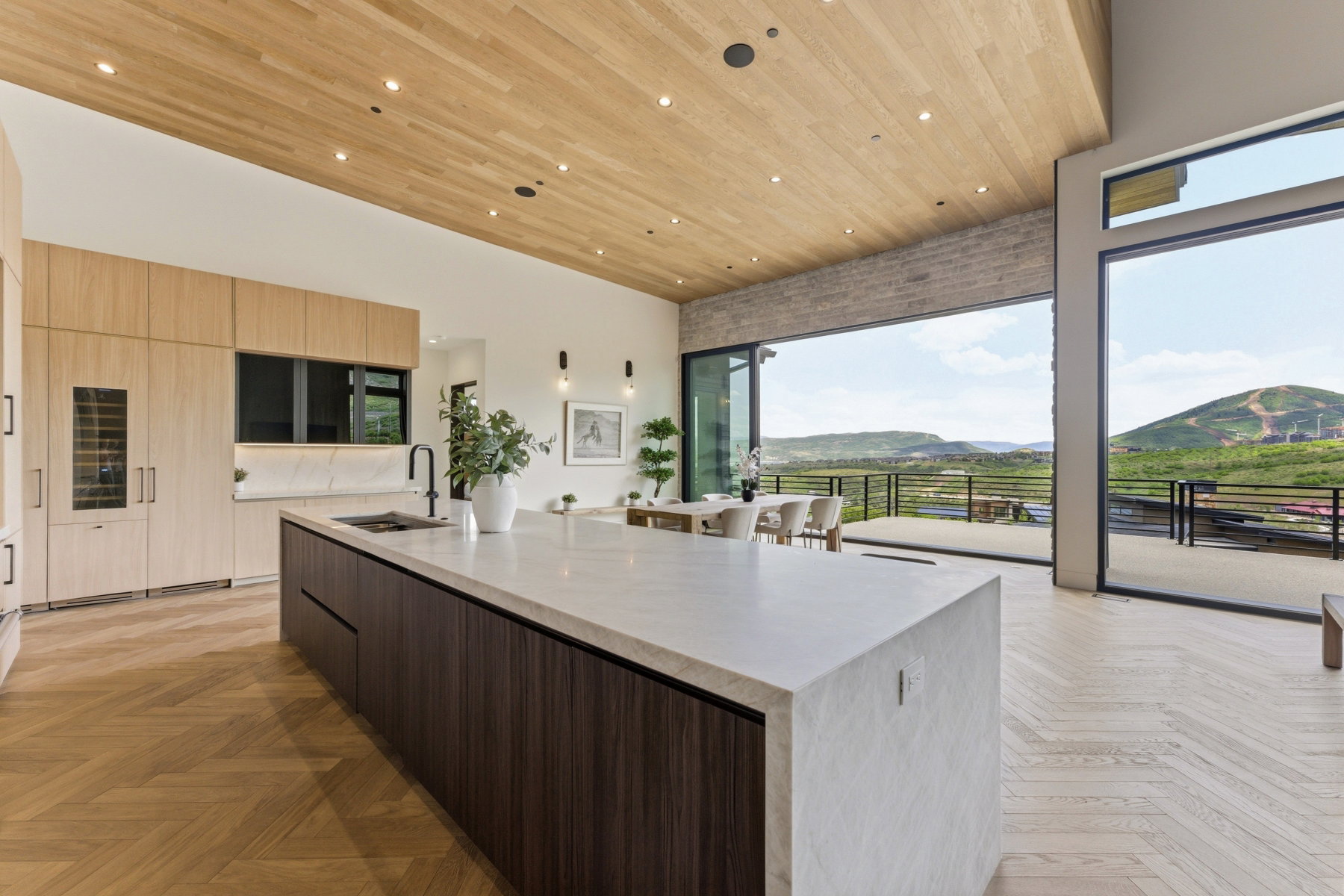 Kitchen featuring a large central island with a light-toned countertop, a built-in sink, and dark wood-finish cabinetry