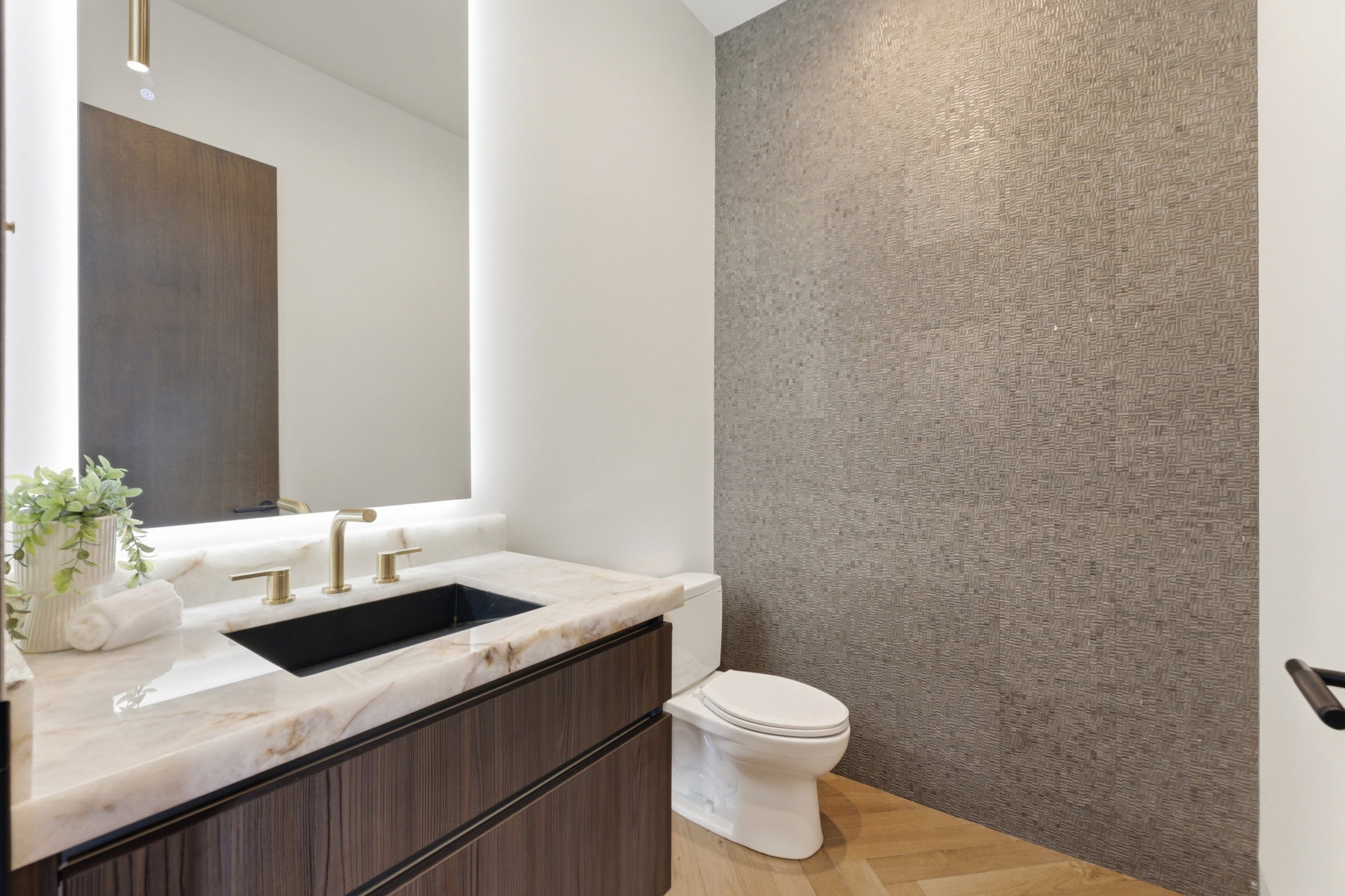 Contemporary powder room featuring a floating wood-finish vanity with a stone countertop, a black undermount sink, and brass-tone fixtures