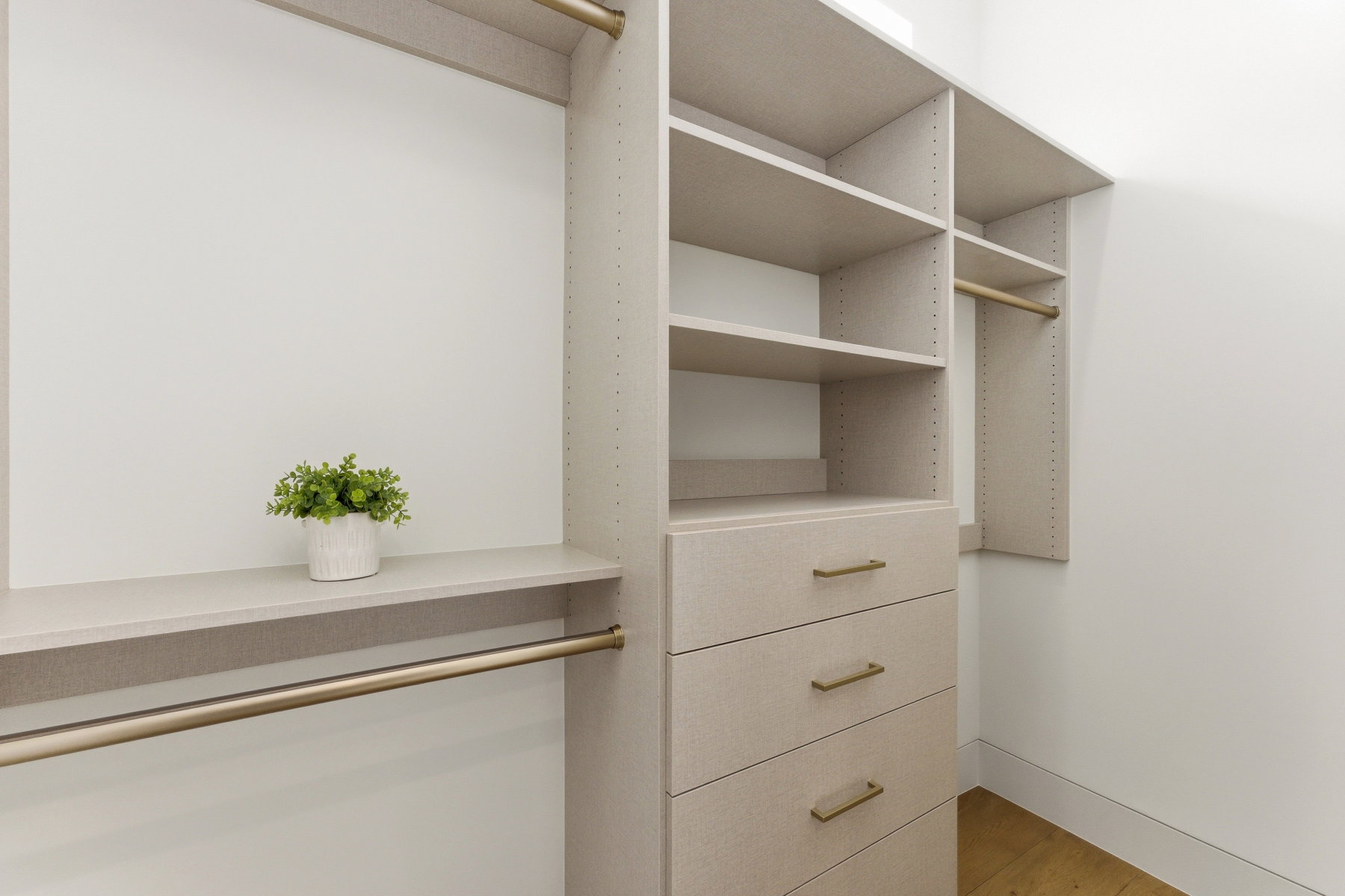 Custom closet system featuring light-toned cabinetry, integrated shelving, and multiple hanging rods
