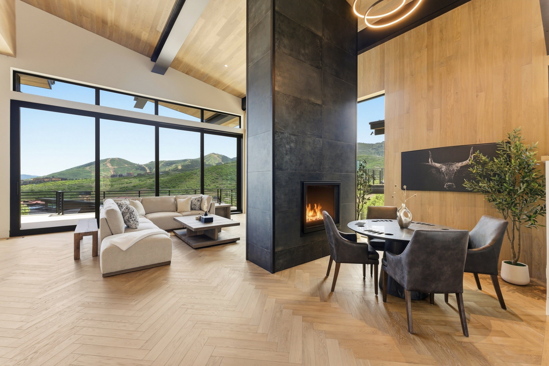 Spacious room with floor-to-ceiling windows, wood-finish flooring in a herringbone pattern, and a vaulted wood-paneled ceiling