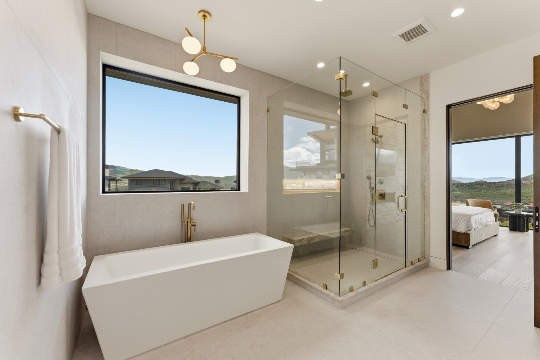 Modern bathroom featuring a freestanding soaking tub, a spacious glass-enclosed shower with a built-in bench, and gold-finish fixtures
