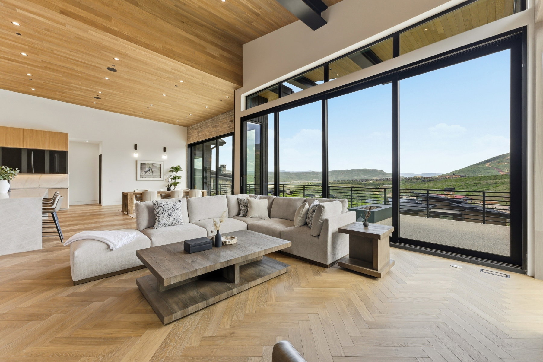 Expansive living area featuring a wood-finish herringbone floor and a wood-paneled ceiling with recessed lighting