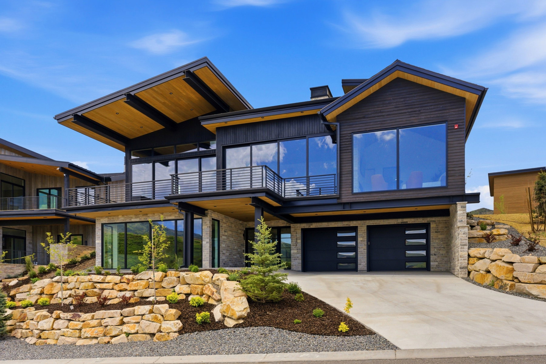 Contemporary exterior featuring dark wood siding, extensive glazing, and stone accents