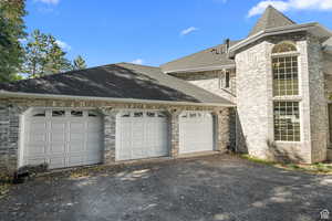 View of home's exterior featuring roof with shingles, asphalt driveway, an attached garage, and brick siding