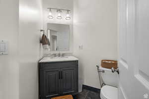 Half bathroom featuring vanity and dark stone finish flooring