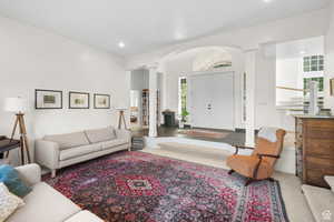 Formal living area featuring arched walkways, a high ceiling, ornate columns, and recessed lighting