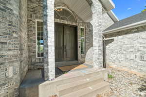 View of exterior front/main entry featuring brick siding and roof with shingles