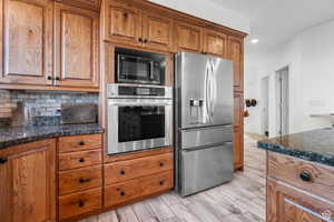 Kitchen with stainless steel appliances, wood finish cabinets, wood tiled floors, and recessed lighting