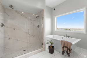 Master bathroom featuring a marble finish shower, a freestanding bath, and light tile patterned floors