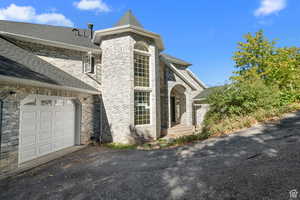 View of front of property featuring roof with shingles, brick siding, driveway, and a garage