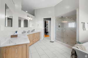 Master bathroom with double vanity, a marble finish shower, a freestanding tub, a spacious closet, and light tile patterned floors