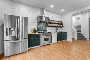 Kitchen #2 featuring stainless steel appliances, butcher block counters, a paneled ceiling, ventilation hood, and light wood-style flooring