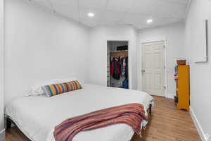 Bedroom featuring a drop ceiling, wood finished floors, a closet, and recessed lighting