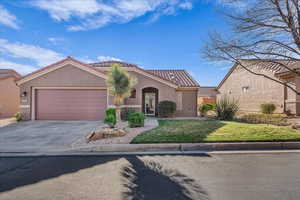 Mediterranean / spanish-style house featuring stucco siding, a tiled roof, a front lawn, and a garage