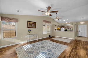 Living room featuring dark wood-type flooring, ceiling fan, and vaulted ceiling