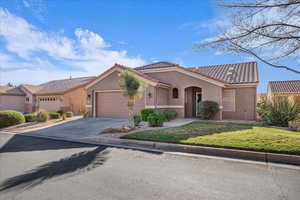 Mediterranean / spanish house featuring stucco siding, a front lawn, a garage, a tiled roof, and concrete driveway
