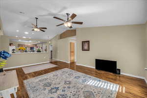 Living area featuring a ceiling fan, dark wood finished floors, lofted ceiling, and suspended lighting