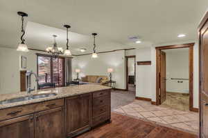 Kitchen featuring light stone counters, dark wood-type flooring, a textured ceiling, open floor plan, and a chandelier