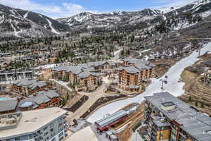 Snowy aerial view with a mountain view and a view of apartment building / complex