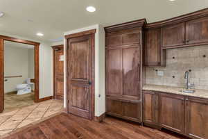 Kitchen with light stone countertops, recessed lighting, backsplash, dark wood finished floors, and dark wood finish cabinets