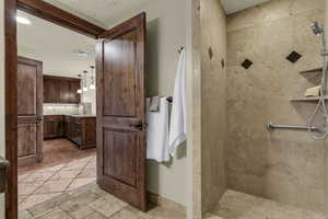 Bathroom featuring stone tile floors, a tile shower, and vanity