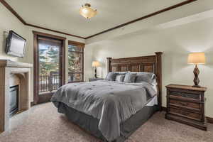 Bedroom featuring ornamental molding, access to exterior, and a fireplace with flush hearth