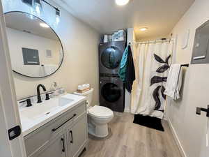 Full bath with a shower stall, vanity, light wood finished floors, and stacked washer and clothes dryer