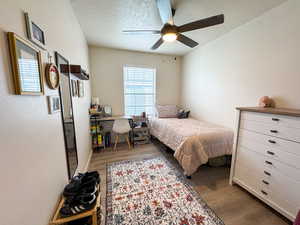 Bedroom featuring a textured ceiling, dark wood-style flooring, ceiling fan, and an office area