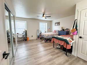 Bedroom with light wood-style flooring, ceiling fan, a closet, and a textured ceiling