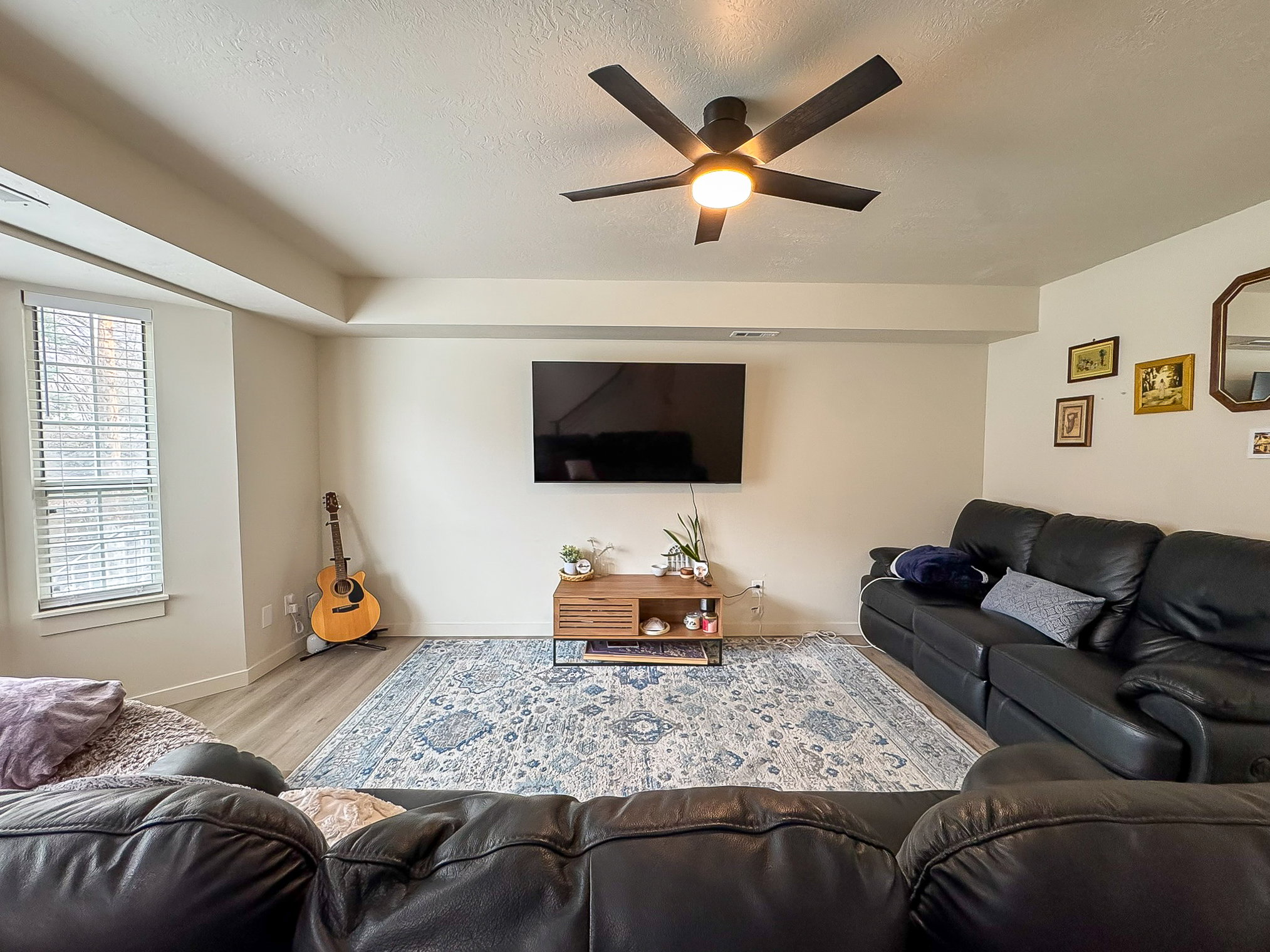 Living room with a ceiling fan, wood finished floors, and a textured ceiling