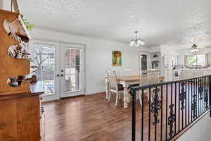 Dining area with a ceiling fan, dark wood-type flooring, a textured ceiling, french doors, and a chandelier