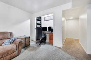 Home office with baseboards and light colored carpet