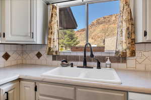 Kitchen featuring light countertops, decorative backsplash, white cabinets, and a mountain view