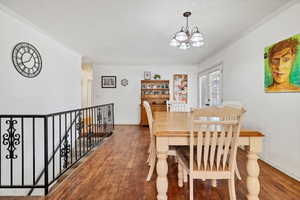 Dining space featuring ornamental molding, hardwood / wood-style floors, and suspended lighting