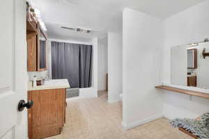 Bathroom with vanity, a textured ceiling, shower / tub combo, and light floors