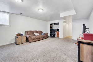 Living room with a desk, light colored carpet, and a textured ceiling