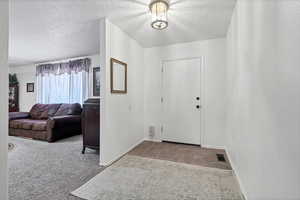 Entrance foyer with a textured ceiling and carpet floors