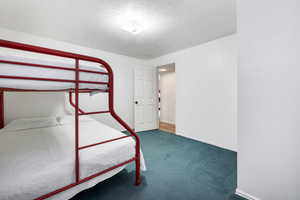 Unfurnished bedroom with dark carpet and a textured ceiling