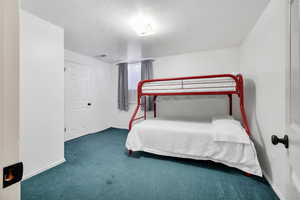Bedroom featuring a textured ceiling and dark carpet