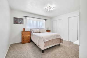 Bedroom with multiple closets and light carpet
