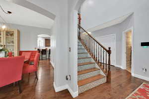 Stairs with arched walkways and hardwood / wood-style flooring